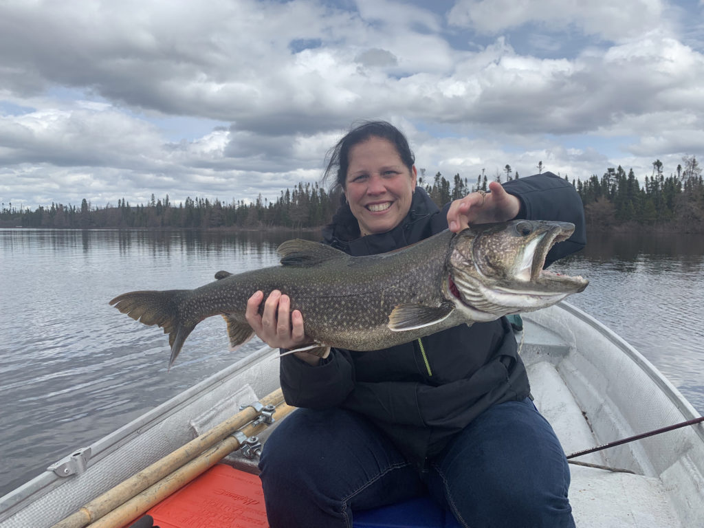 Une femme qui tient une poisson qu'elle a pêché dans ses mains sur une rivière au Labrador