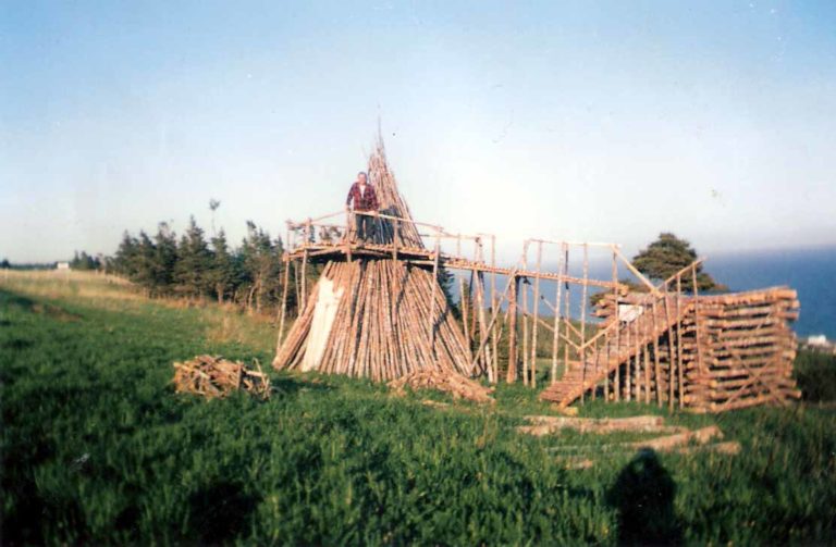 Tente Mi’kmaq traditionnelle, une structure en bois construite sur un terrain de gazon dans une forêt