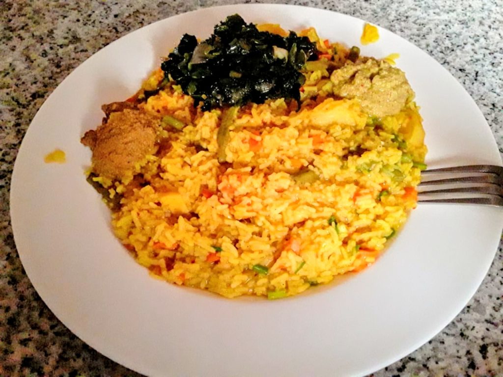 Un plat de ris jaune, avec des légumes vert sur un côté et rouge au milieu.