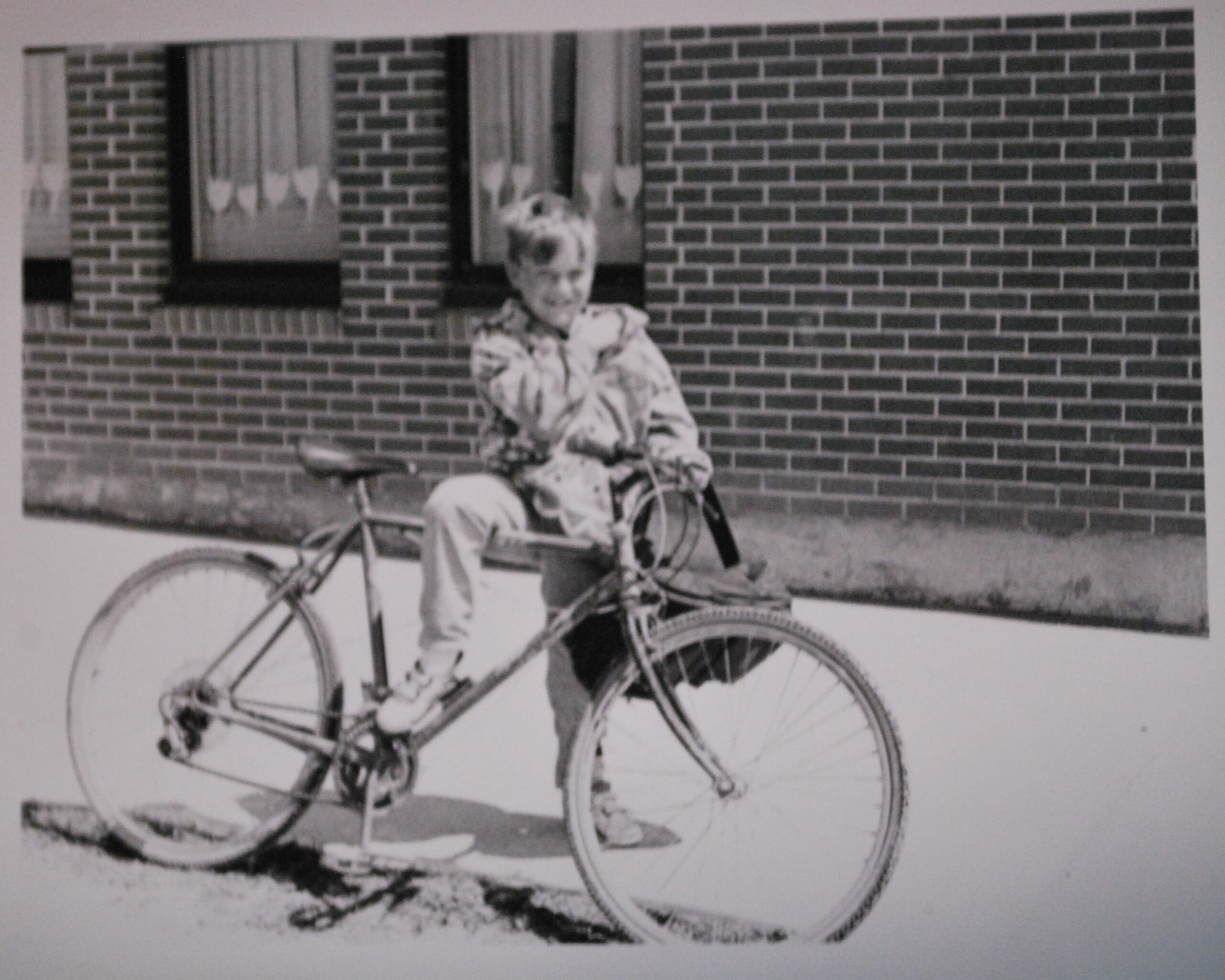 Une photo noire et blanc d'un jeune garçon avec une bicyclette.